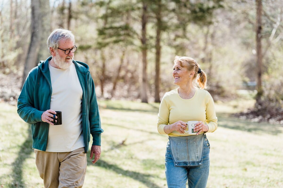 An older couple walking outdoors together, talking.