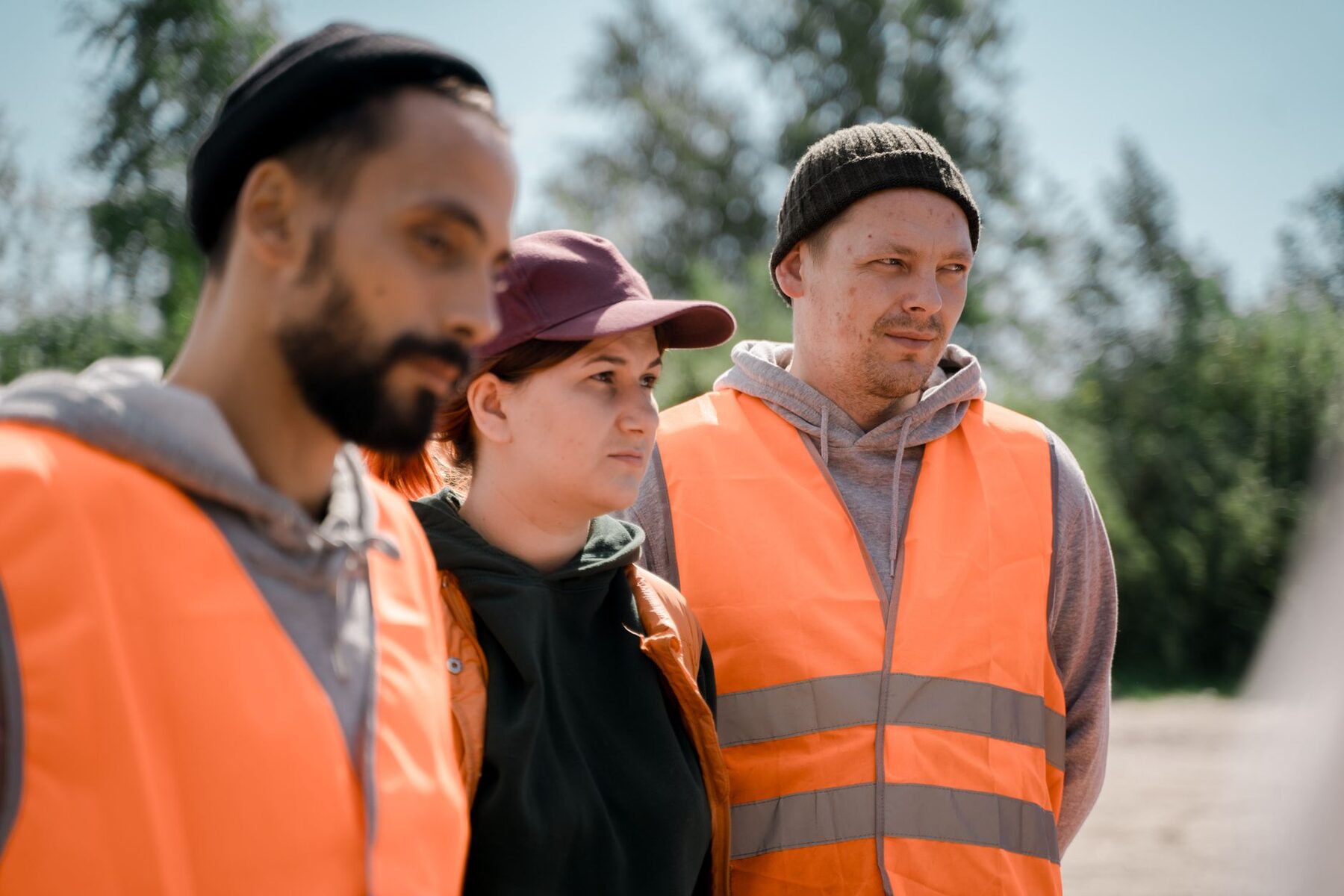 Three workers in high visibility vests standing together outdoors on a job site.